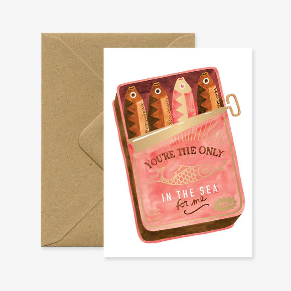 A greeting card with a illustration of fish in a can with the text 'YOU'RE THE ONLY ONE IN THE SEA FOR ME' on it, presented with a brown envelope.