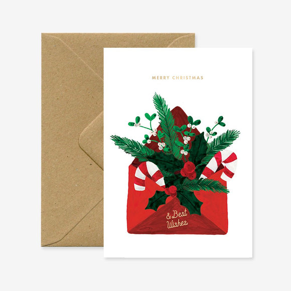 A Christmas greeting card with a red envelope design and green foliage, accompanied by a brown envelope.