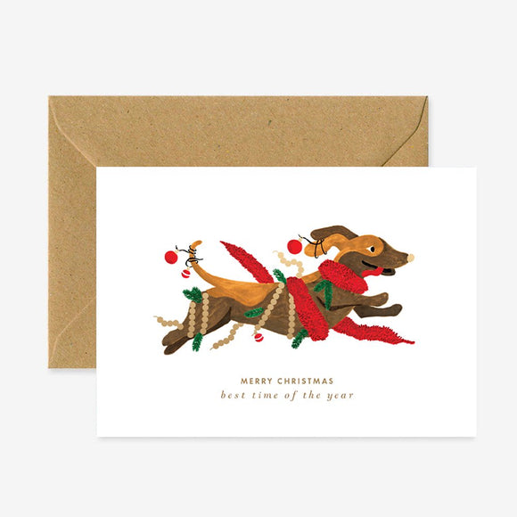 A Christmas themed greeting card depicting a decorated dog with the text 'Merry Christmas - best time of the year' and a brown envelope.