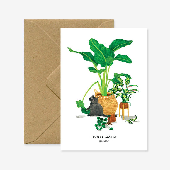 A greeting card with an illustration of a cat among houseplants, with a brown envelope.