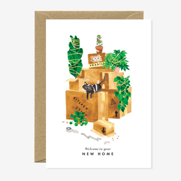 Greeting card with an illustration of a cat on top of moving boxes with plants, and text that reads 'Welcome to your NEW HOME'.