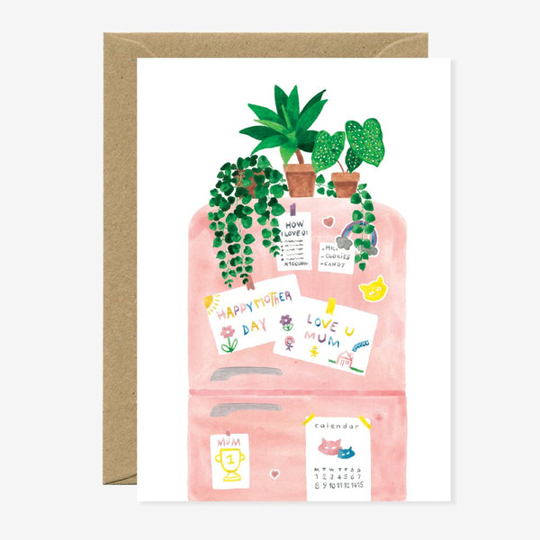 A greeting card with an illustration of a refrigerator with notes and plants on it, accompanied by a brown envelope.