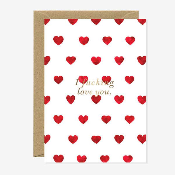 A white greeting card with a pattern of red hearts and the phrase 'I f*cking love you' in gold foil at the center. A brown envelope is included.