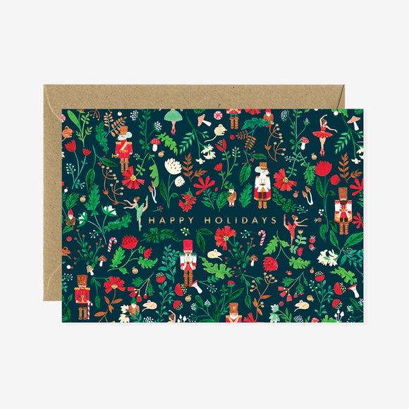 A Christmas greeting card with a floral and nutcracker pattern and the text 'HAPPY HOLIDAYS' on it, accompanied by a brown envelope.
