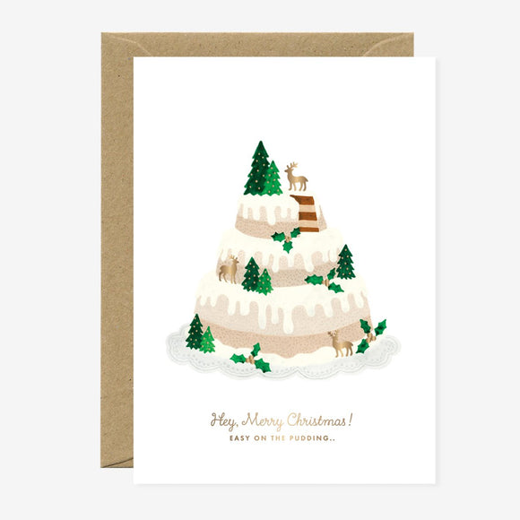 A Christmas themed greeting card depicting a layered cake with reindeer and trees on it, accompanied by a brown envelope.