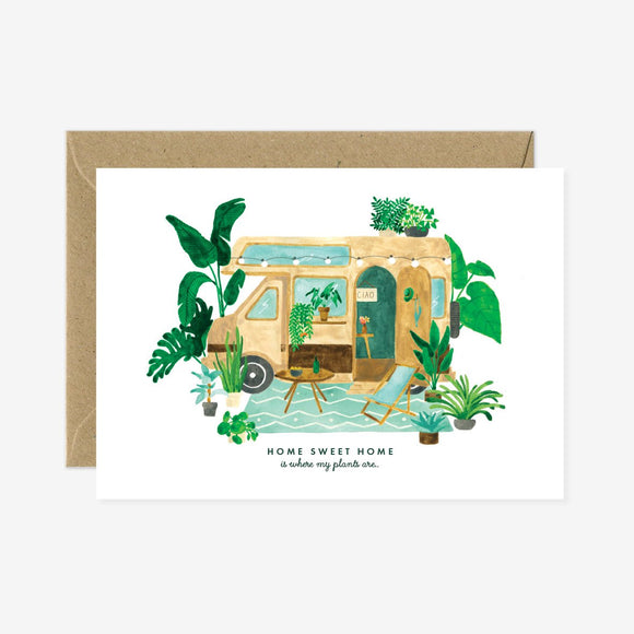 A greeting card with an illustration of a houseboat and surrounding plants, with a accompanying brown envelope.