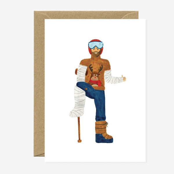 A greeting card featuring an illustration of a person with ski gear and a humorous pose, titled 'Ski Fail Man'. The card is shown with a natural white envelope.