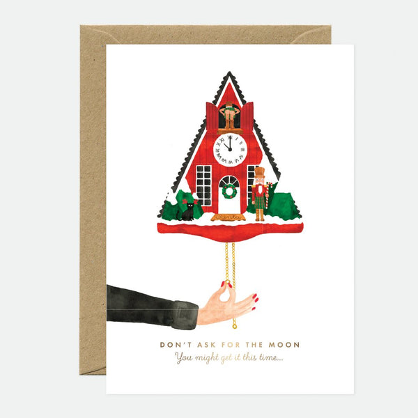 A Christmas themed greeting card featuring a red and gold cuckoo clock with a hand reaching out, accompanied by a brown envelope.