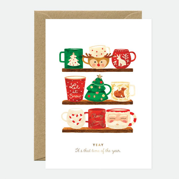 A Christmas-themed greeting card with various illustrated mugs and holiday motifs, accompanied by a brown envelope.