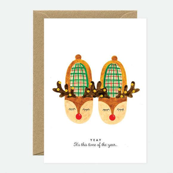 A Christmas greeting card with a illustration of two reindeer heads wearing festive hats, with a brown envelope.