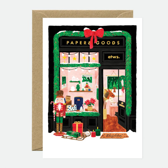 Illustrated Christmas greeting card depicting a shop front with holiday decorations, a nutcracker, and presents.