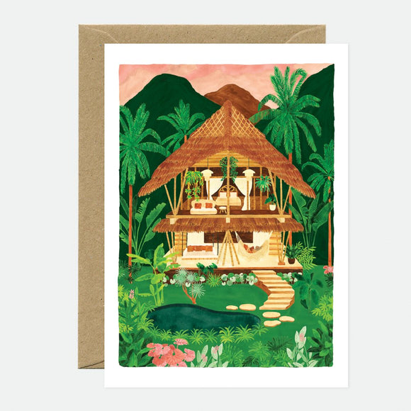 Illustrated greeting card depicting a tropical scene with a thatched roof hut, surrounded by palm trees and flowers, with a gold envelope.