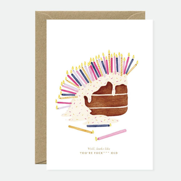 Greeting card with an illustration of a cake with gold foil details and colorful candles, accompanied by text and a recycled brown envelope.