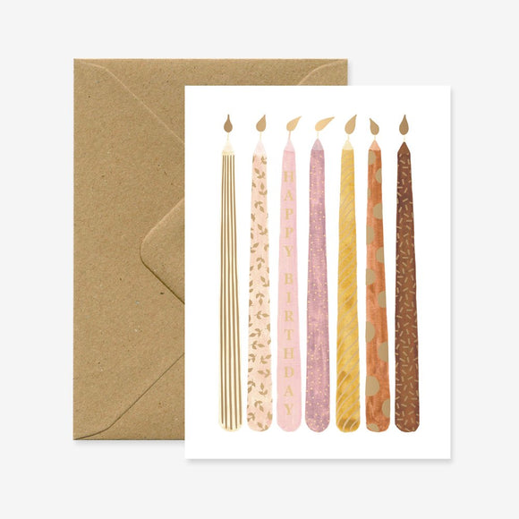 A birthday greeting card with gold foil details depicting various candles, accompanied by a brown envelope.