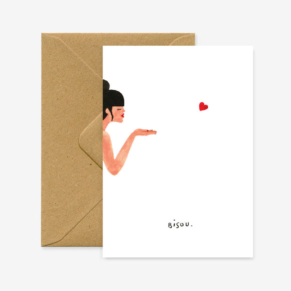 A greeting card with a illustration of a person blowing a kiss, accompanied by the word 'bisou' on the bottom, presented with a brown envelope.