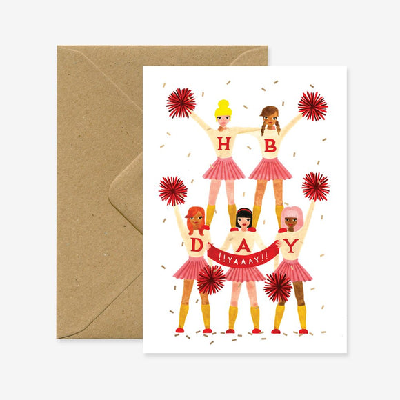 Illustration of five cheerleaders on a birthday greeting card with the text 'HAPPY BIRTHDAY' and a recycled brown envelope.