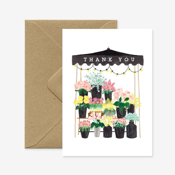 A thank you greeting card with a floral market illustration, accompanied by a brown envelope.