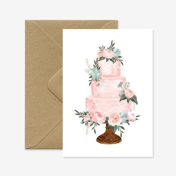 A greeting card with a floral wedding cake illustration, accompanied by a brown envelope.