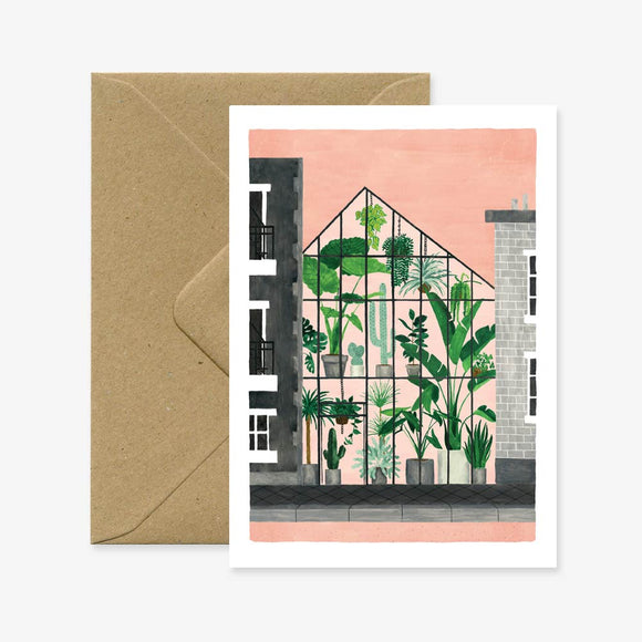 A greeting card with an illustration of a greenhouse full of plants, accompanied by a brown envelope.
