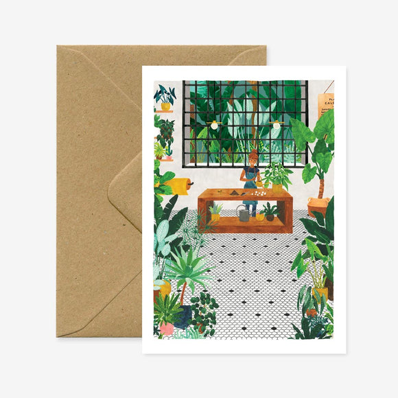 A greeting card with an illustration of a person gardening, surrounded by various plants. The card is accompanied by a brown envelope.