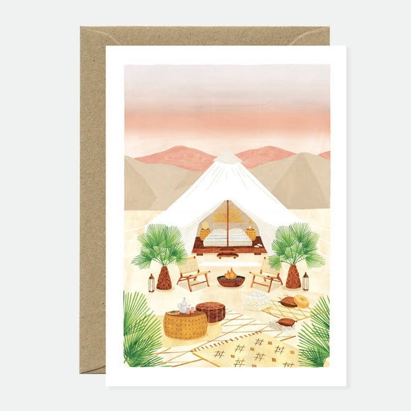 Greeting card with an illustration of a tent and outdoor furniture in a desert landscape, accompanied by a recycled brown envelope.