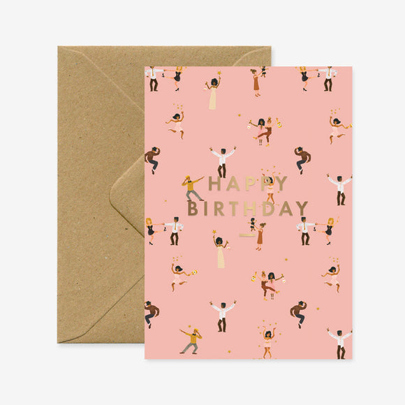 A pink A6 birthday greeting card with a pattern of illustrated people dancing and the text 'HAPPY BIRTHDAY' in capital letters, accompanied by a brown envelope.