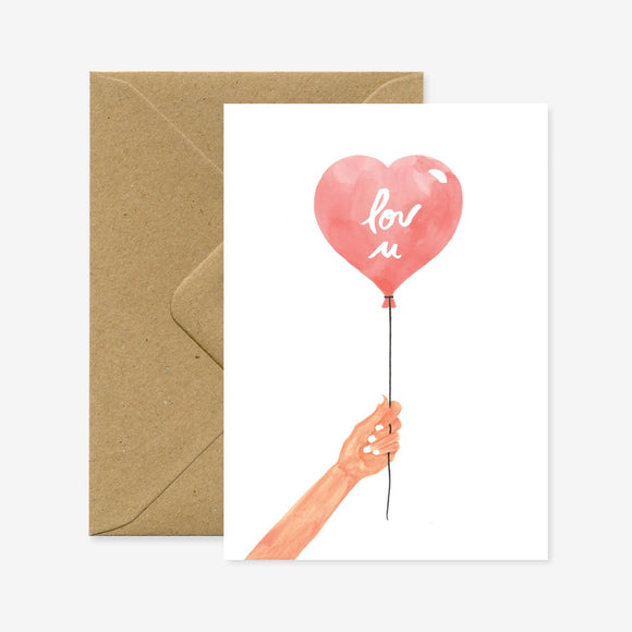 A greeting card with a illustration of a hand holding a red heart-shaped balloon with the word 'lov u' written on it, accompanied by a brown envelope.