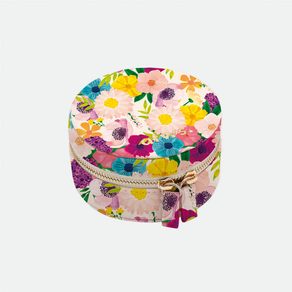 A round jewellery box with a floral pattern in shades of pink, yellow, and green, closed with a gold-colored zipper.