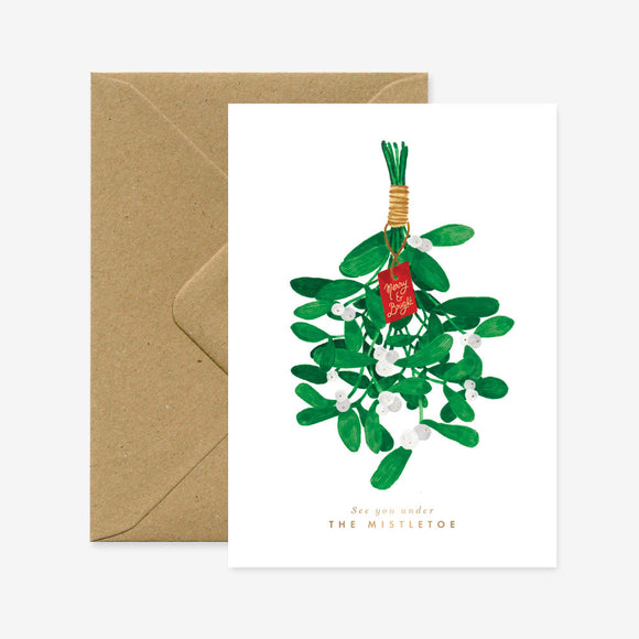 A Christmas greeting card featuring an illustration of mistletoe with gold foil details, accompanied by a brown envelope.