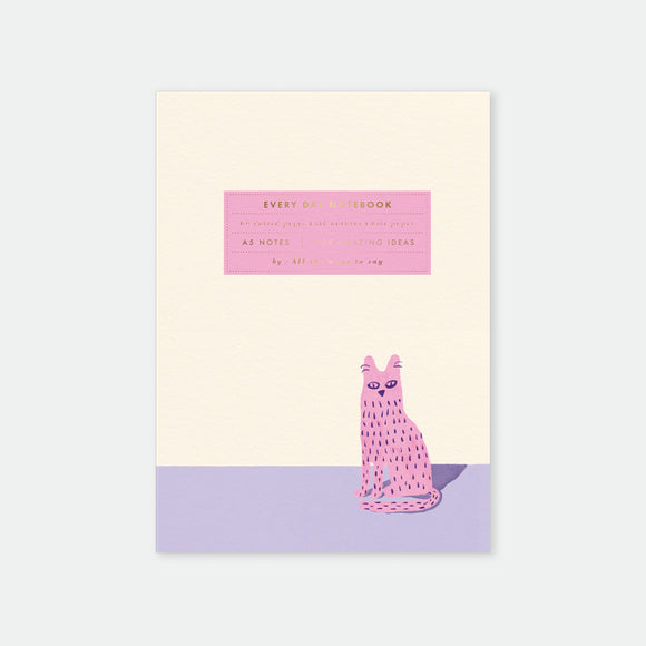 A5 notebook with a cover illustration of a lonely cat sitting on a floor with a pink and purple background. The text on the cover is minimalistic and poetic.