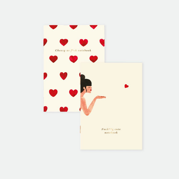 Two pocket notebooks, one with a gold foil heart pattern and the name Bisou, and another with an illustration of a person holding a notebook with the text 'Passion cute notebook'.