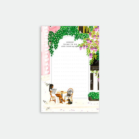 A notepad with an illustration of a person reading a book in a garden setting with flowers and a chair.