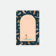 A notepad with a water-inspired design featuring paddleboarding girls. The notepad has a peach-colored cover with a semi-circular cut-out revealing part of the design inside.