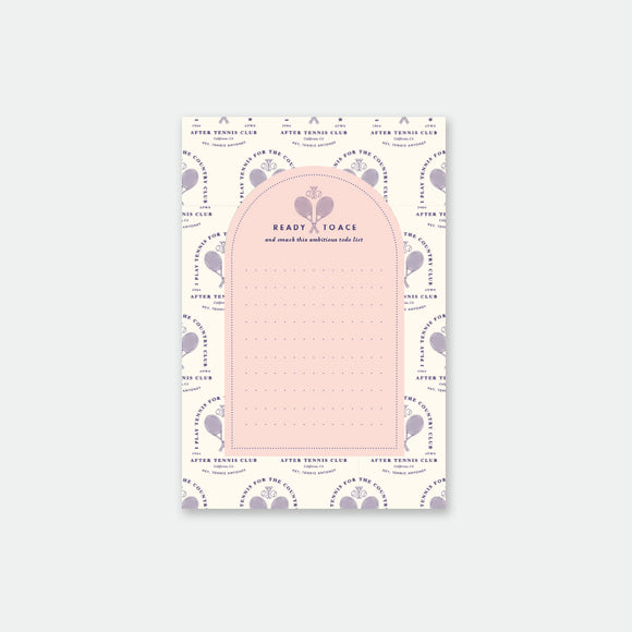 A notepad with a tennis-inspired design, featuring sports equipment and motifs in a pink color scheme.