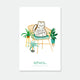 Feline Good enamel pin by All the Ways to Say featuring white cat with “Feline Good” text, gold-plated details, displayed on cozy chair with green plants background.