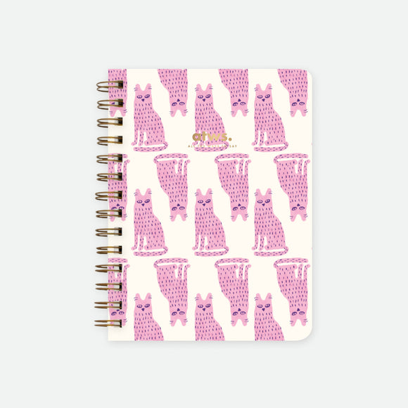 A spiral notebook with a white cover featuring a pattern of pink cats in various playful poses.