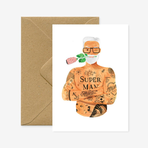 A greeting card featuring an illustration of a character named 'Super Max' with a floral pattern, wearing glasses and a costume. The card is A6 size and is shown with a brown envelope.