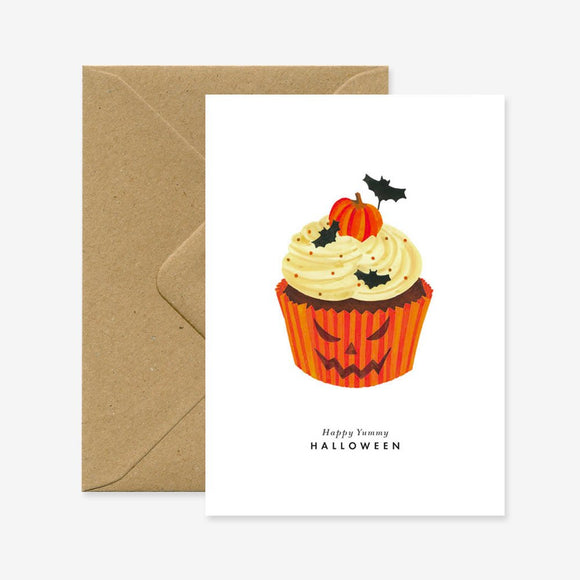 Halloween themed greeting card featuring an illustration of a cupcake with Halloween decorations, accompanied by a brown envelope.