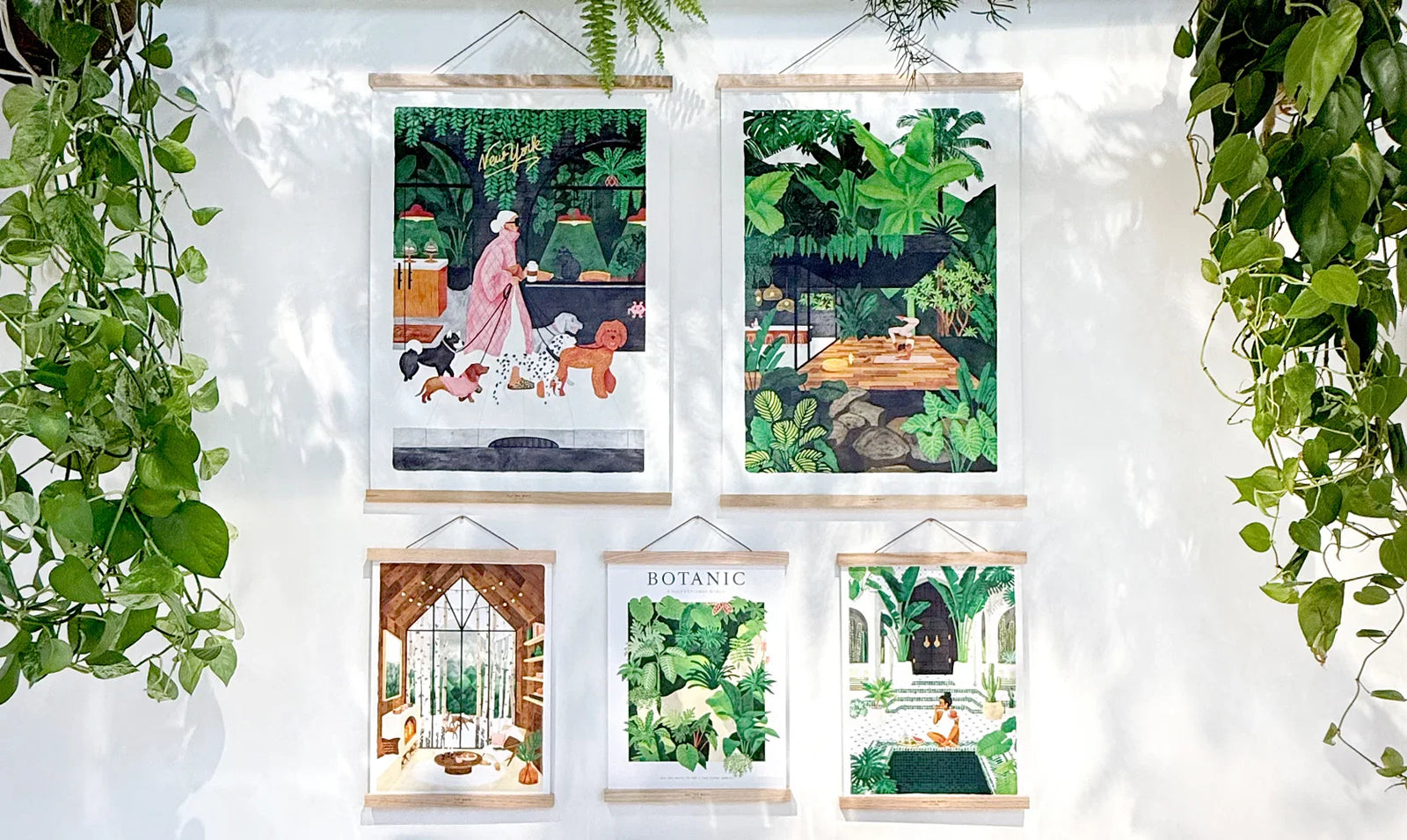 All the Ways to Say wooden hangers – framed botanical and lifestyle art prints hanging on a white wall with green plants