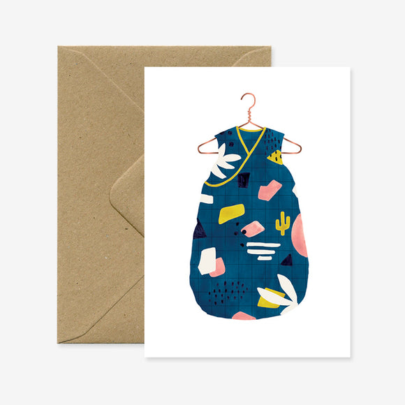 Greeting card with illustration of a colorful baby sleeping bag in blue with playful patterns, symbolizing the arrival of a baby boy.