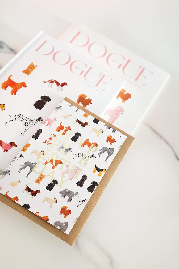 Birthday card illustrated with colorful dogs and gold foil “Happy Birthday” text, placed on a kraft envelope.