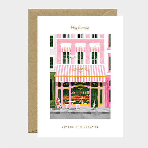 Illustration of a pink building with a striped awning on a greeting card.