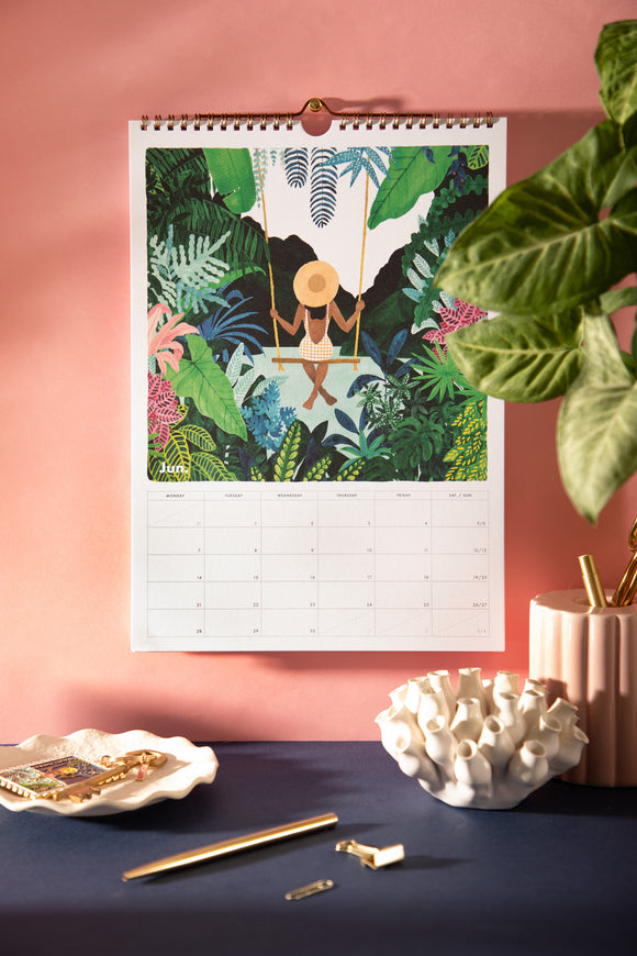 June page of the 2027 ATWS wall calendar: woman in a straw hat on a swing in a lush tropical jungle