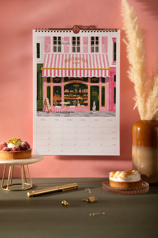 November page of the 2027 ATWS wall calendar showing a pink striped Parisian bakery front with a dalmatian