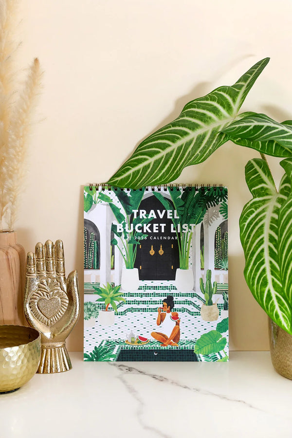 Travel Bucket List 2026 calendar by All The Ways To Say displayed with tropical plants and gold decor