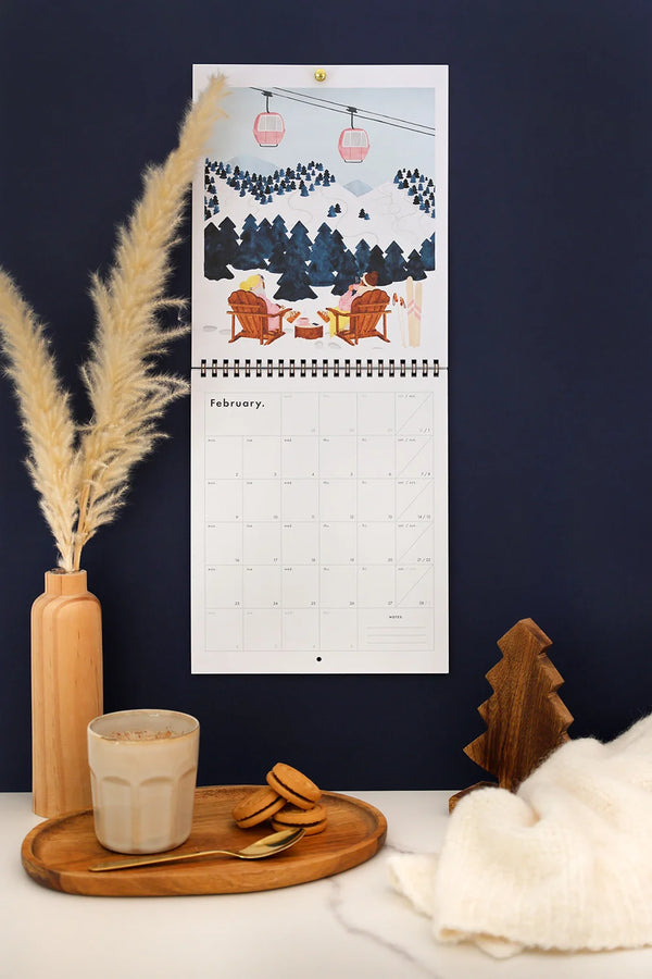 February page of Travel Clichés 2026 calendar – ski resort scene with cable cars and mountain view
