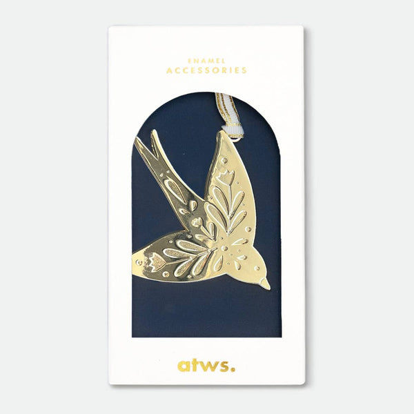 A gold-plated enamel Christmas ornament in the shape of a swallow, packaged on a navy-colored card with 'ATWS' branding.