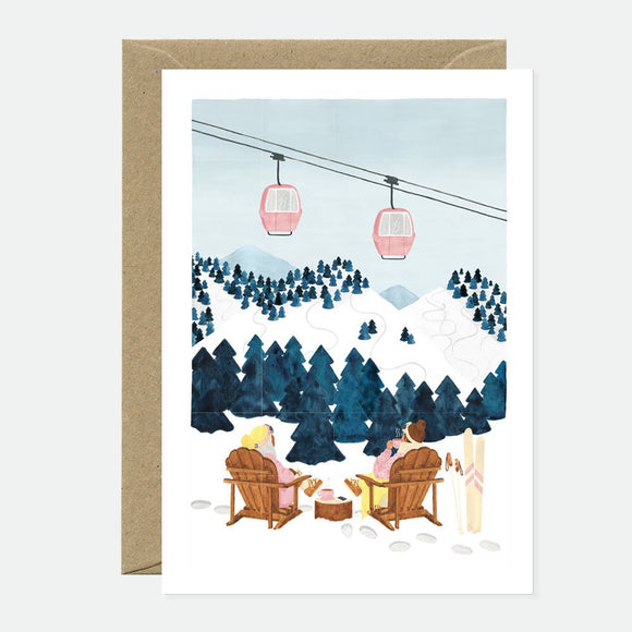 Greeting card showing a snowy alpine landscape with pine trees, two people sitting in wooden chairs, and pink cable cars above the mountains.
