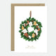 Greeting card with an elegant Christmas wreath decorated with pinecones, gingerbread cookies, dried oranges, and white flowers, with gold foil accents.