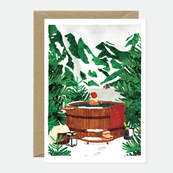A greeting card with an illustration of a wooden hot tub in a snowy forest setting, accompanied by a recycled brown envelope.